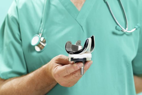 Knee Replacement Surgeon Doctor shows artificial knee